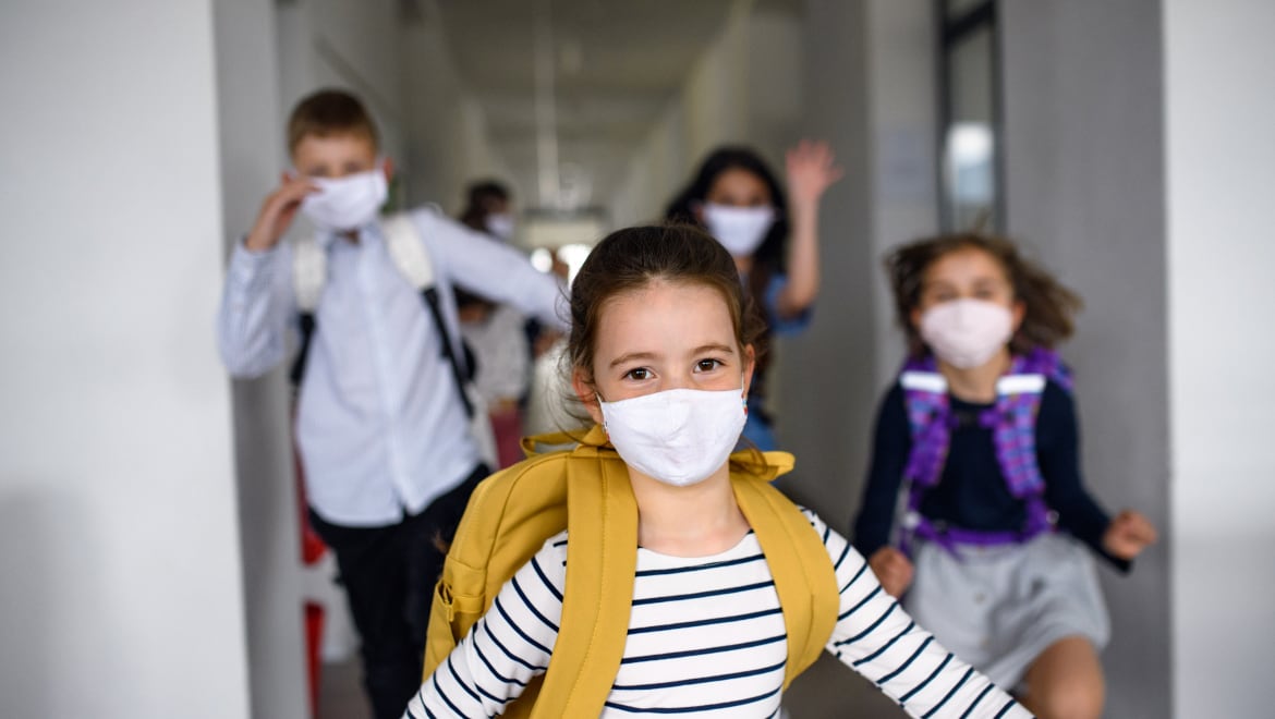 Child wearing a mask and a backpack, smiling expression